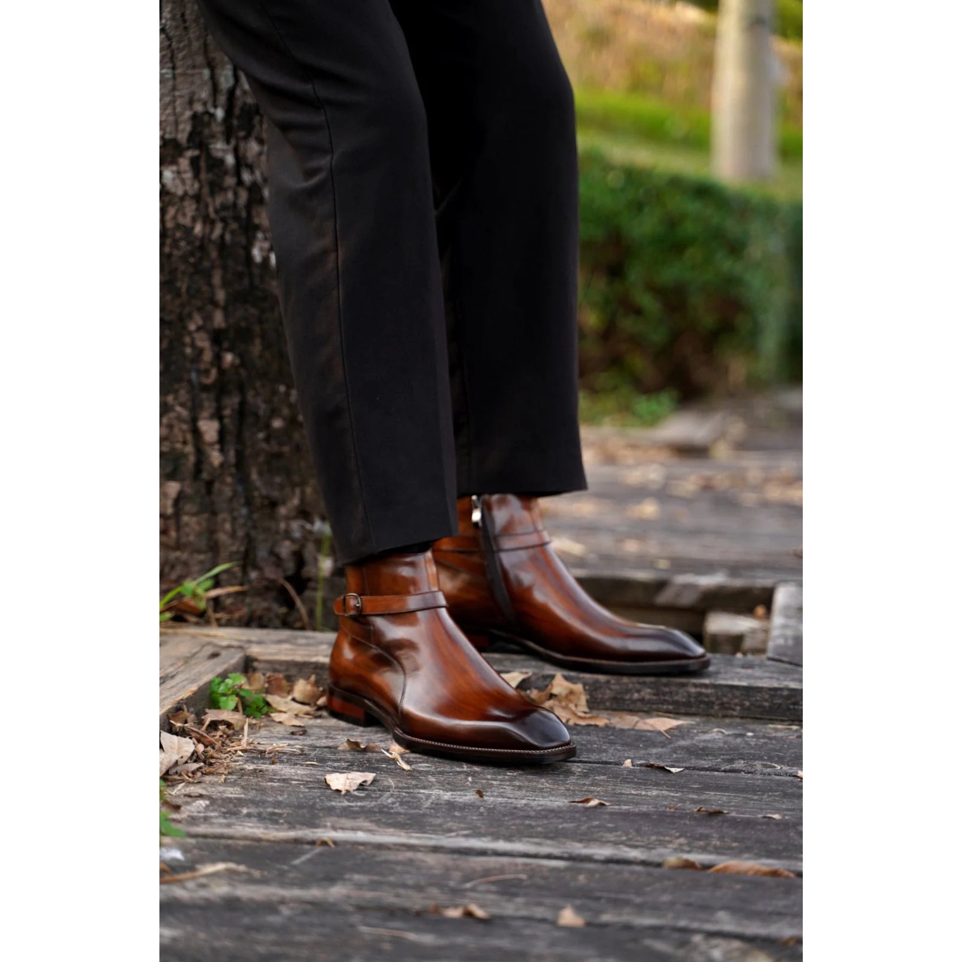 Brown Leather Jodhpur Boots with a patina finish, featuring a sleek ankle strap and polished design, worn with tailored trousers in an outdoor setting.