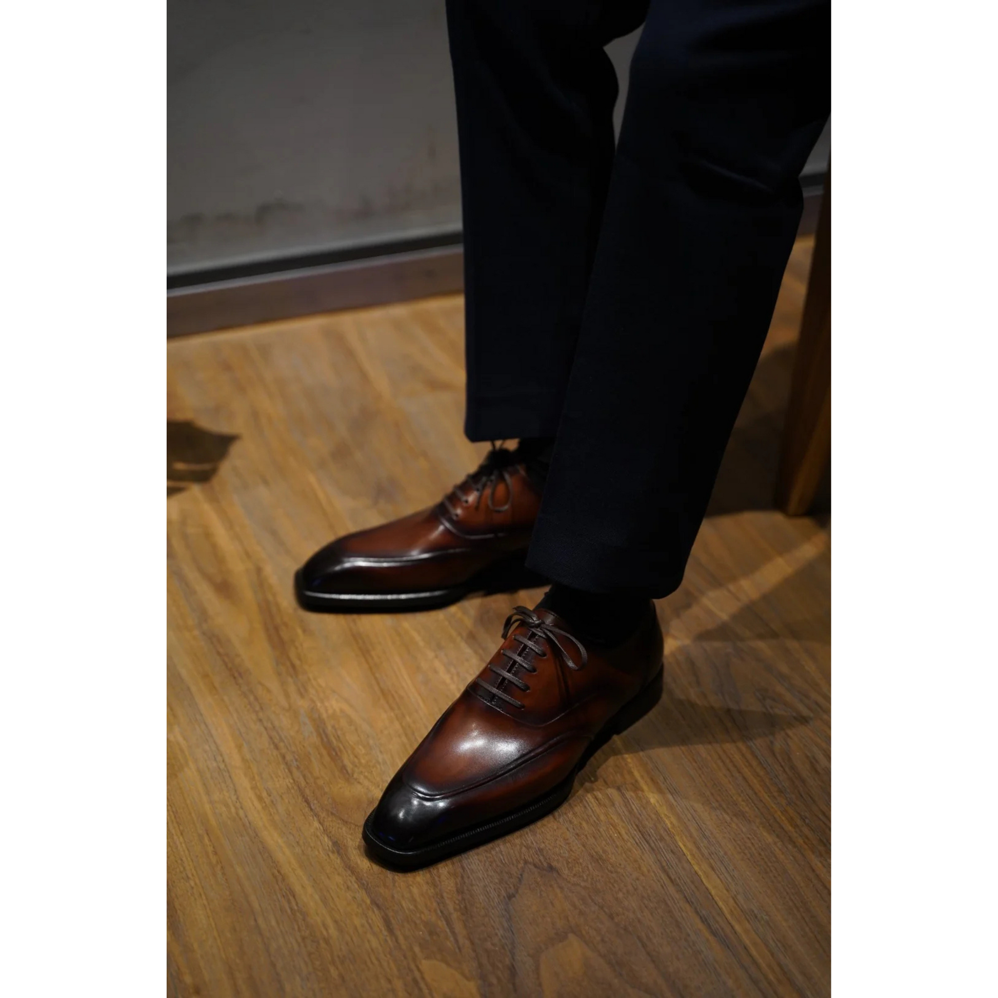Hand-Polished Brown Wholecut Oxford Shoes with Patina Finish worn with formal trousers, showcasing sleek design, premium craftsmanship, and luxurious patina.