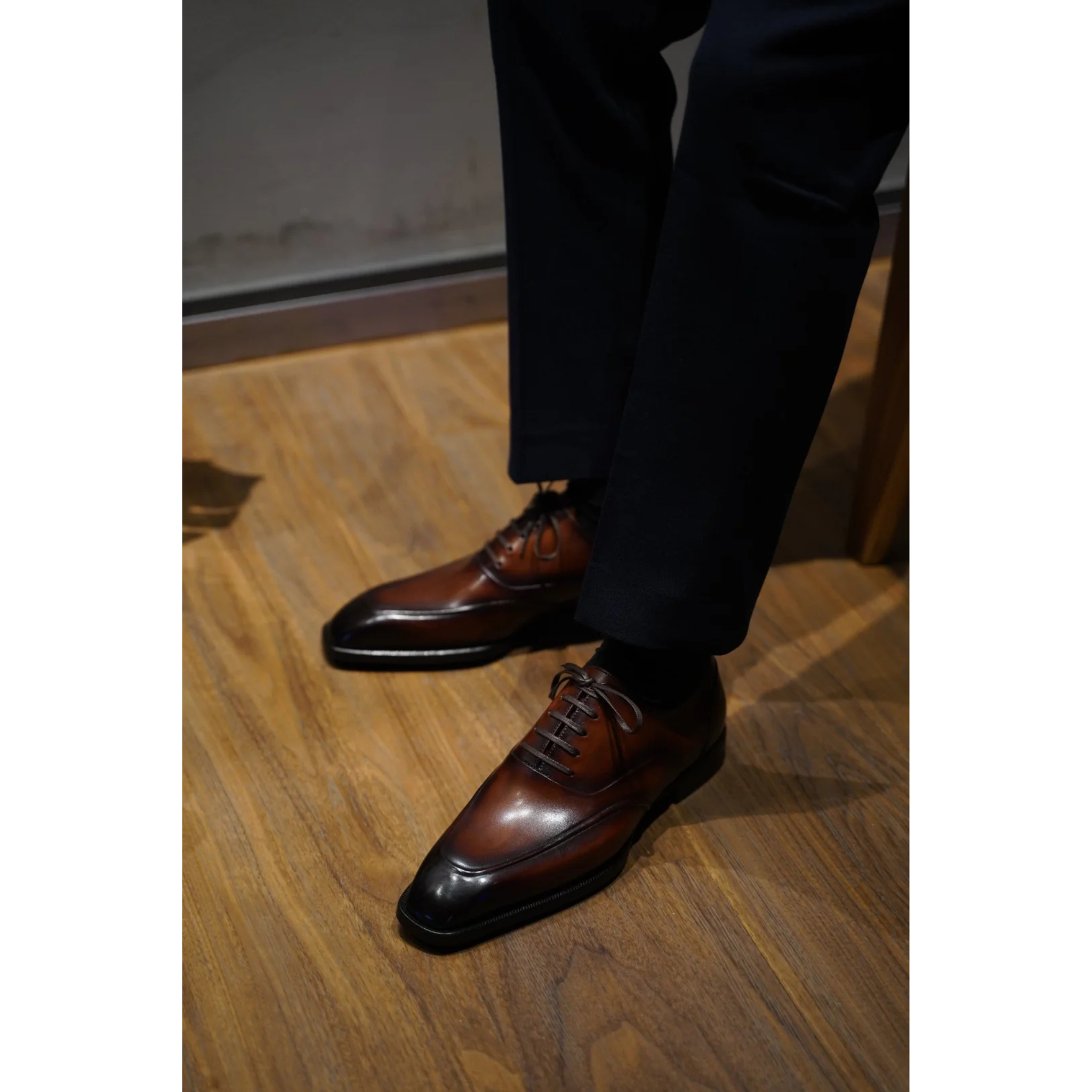 Hand-Polished Brown Wholecut Oxford Shoes with Patina Finish worn with formal trousers, showcasing sleek design, premium craftsmanship, and luxurious patina.