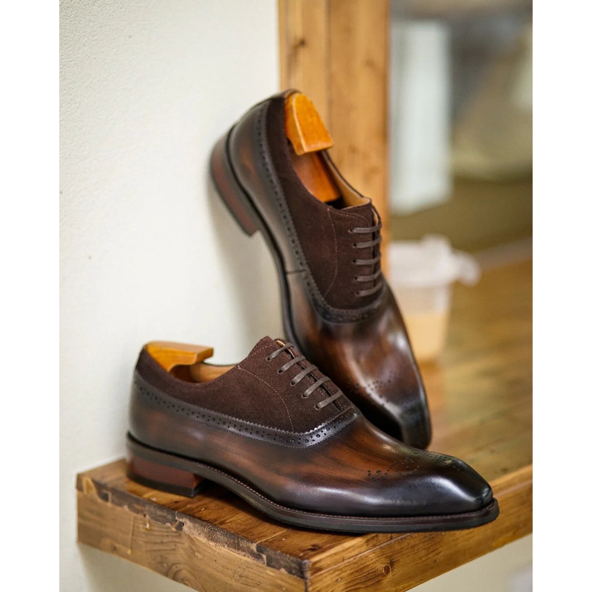 Elegant brown leather oxford shoes with suede panels, featuring brogue perforations and a polished finish.