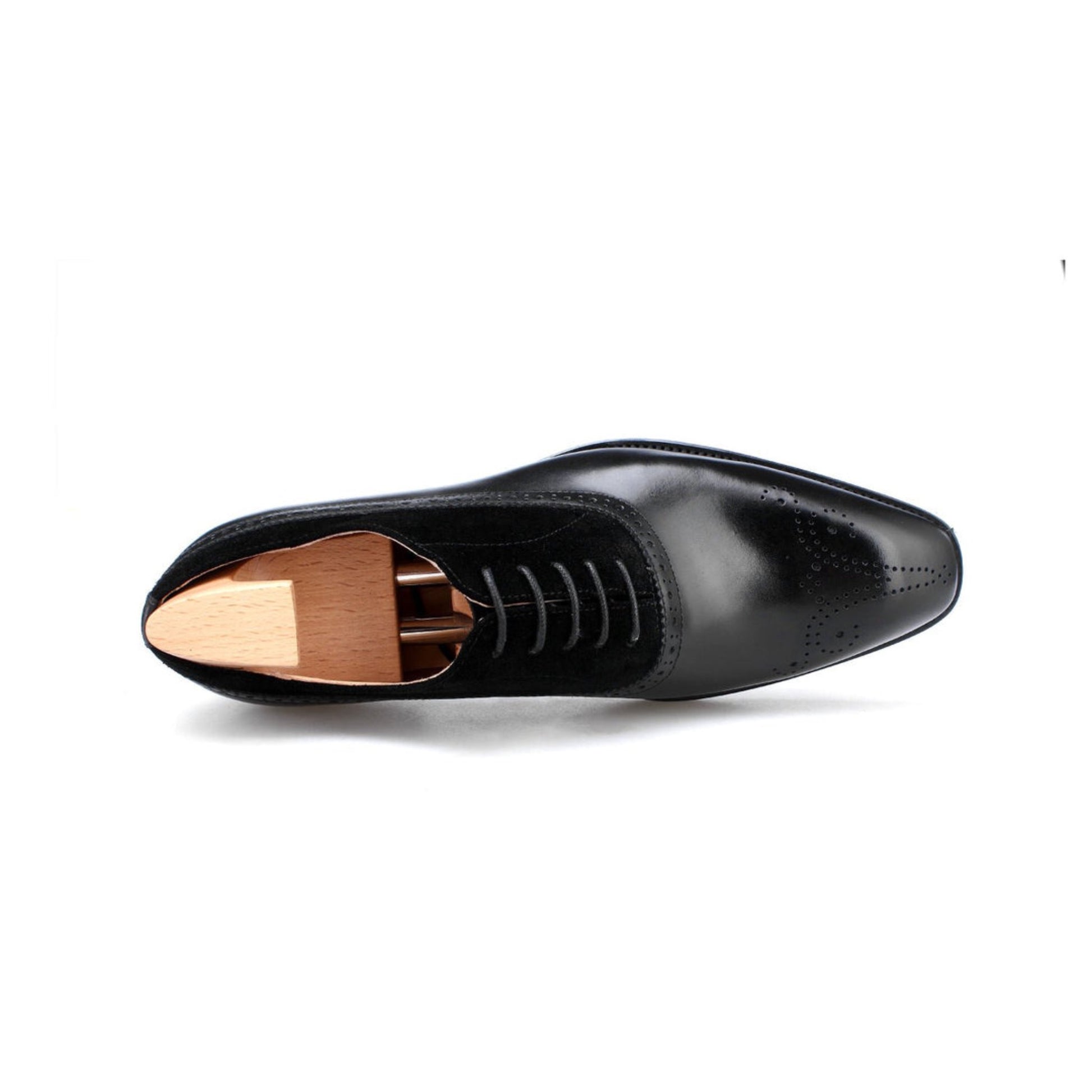 Top-down view of black suede and leather oxford shoes with elegant brogue perforations and wooden shoe trees.