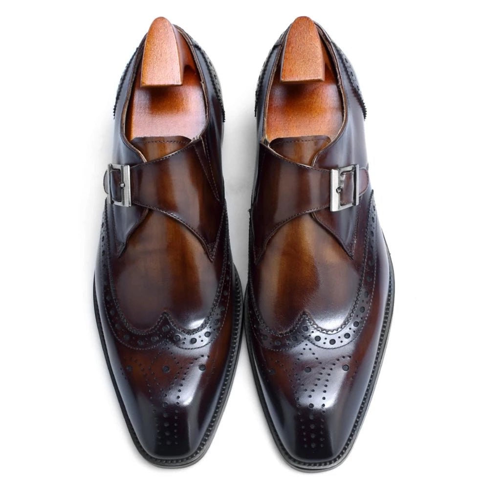 Overhead view of tan leather single monk strap shoes with brogue detailing and wooden shoe trees inside.