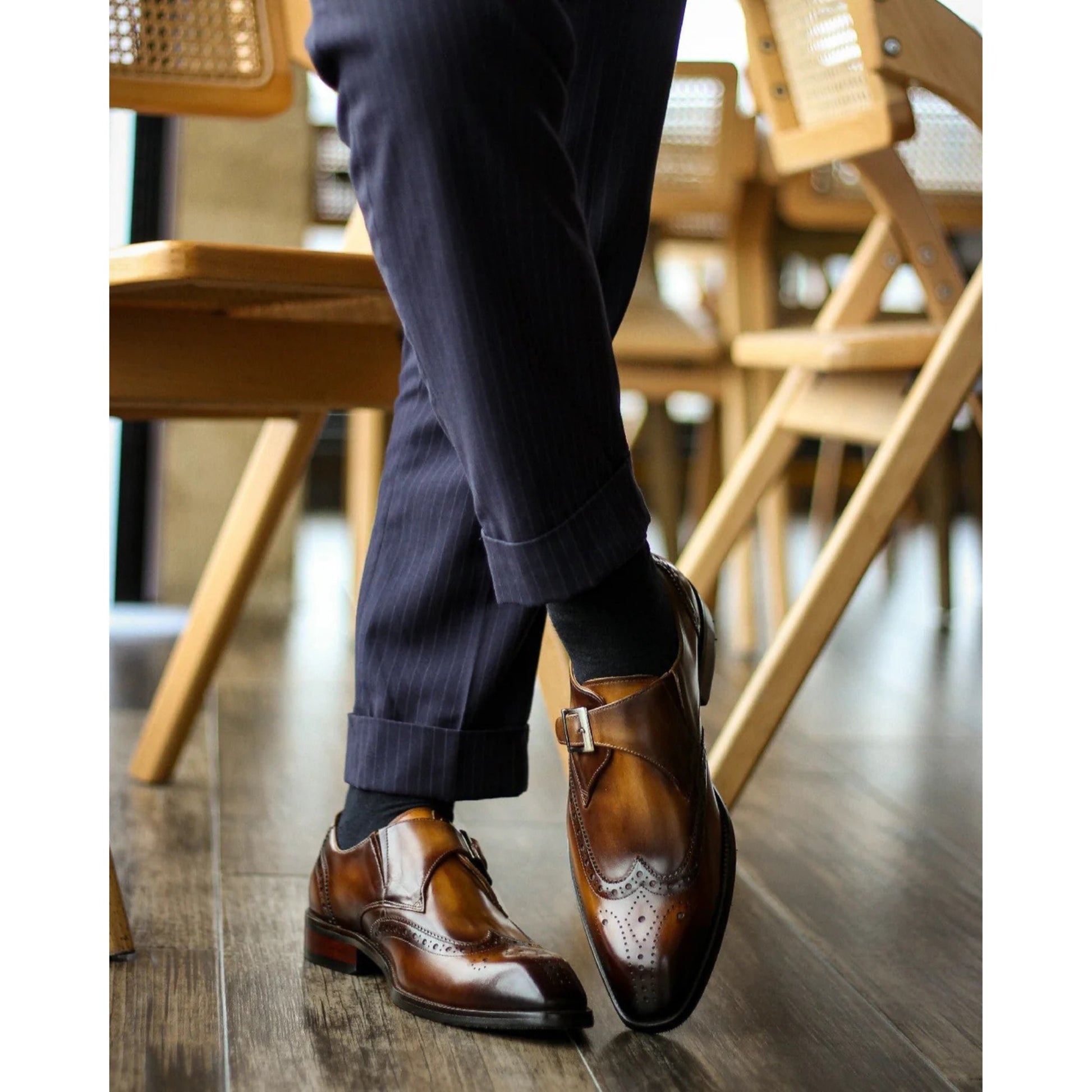 Profile view of tan leather single monk strap shoes featuring brogue detailing and shiny finish.