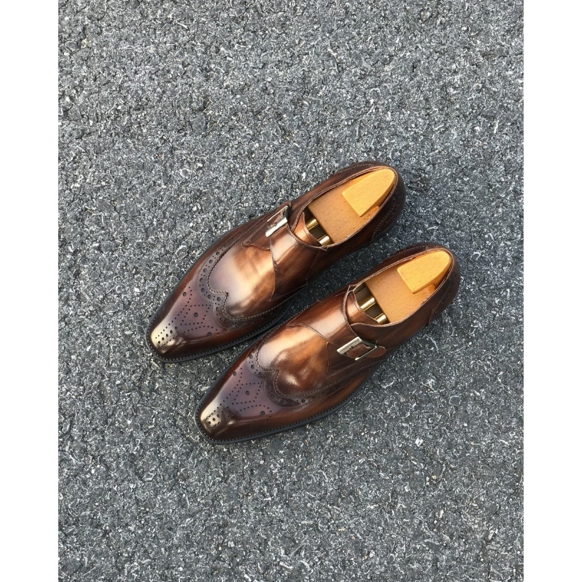 Top view of tan leather single monk strap shoes with intricate brogue detailing and metal buckle.
